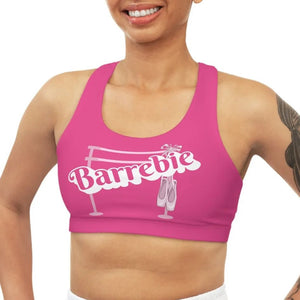 A bright pink Barbie inspired racerback sports bra for women. The original design features a ballet barre and pointe shoes.