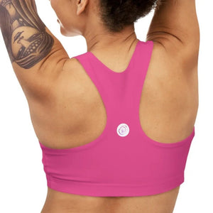 A bright pink Barbie inspired racerback sports bra for women with a dancewear store logo on the back, shown on a model.